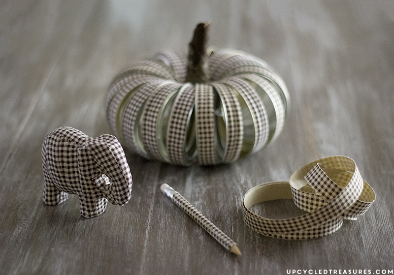 See how easy it is to create this rustic fall mason Jar lid pumpkin using canning lids, fabric tape, fishing line and a stick!