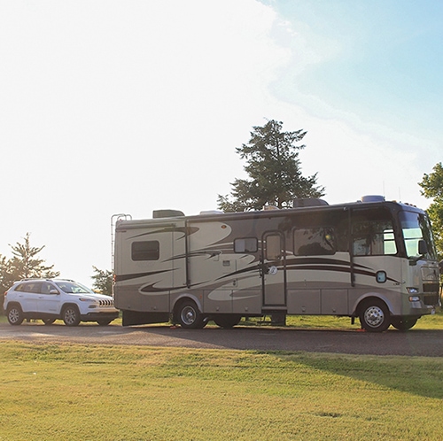 Our RV with the car behind it in the featured image for From Nowhere to Now here