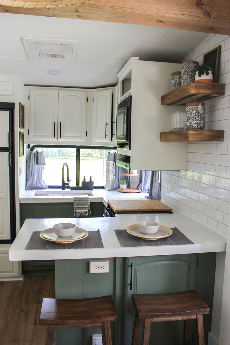 This remodeled RV kitchen has green cabinets and white concrete counters. Featuring @karleeandweston on MountainModernLife.com